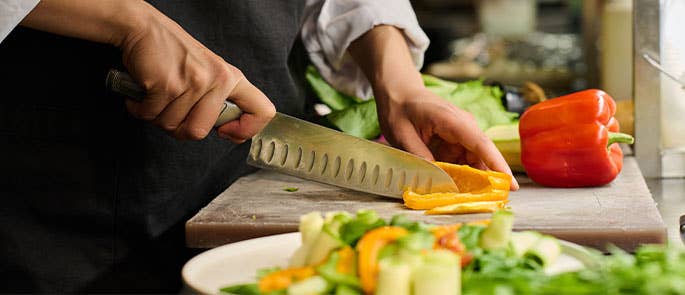 chef chopping a pepper on chopping board