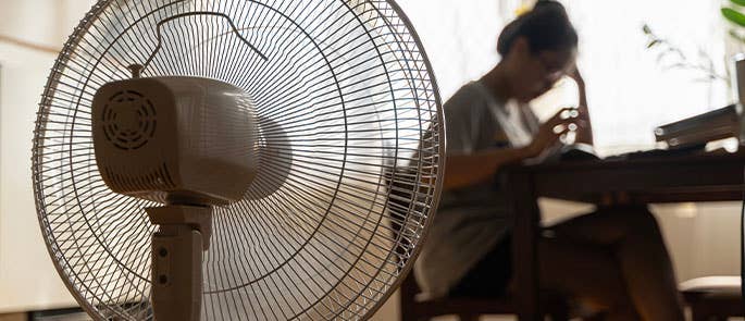 person sat at a table in front of a cooling fan