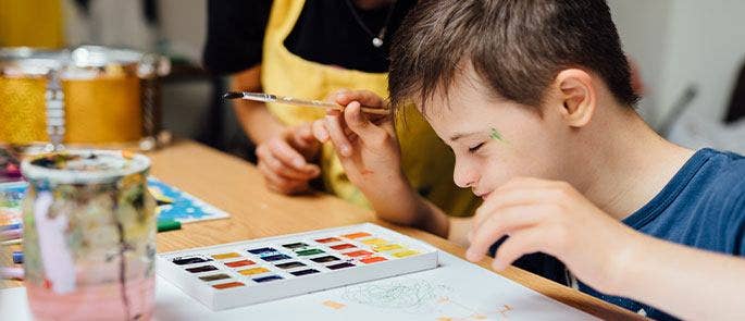 Young boy painting in a class