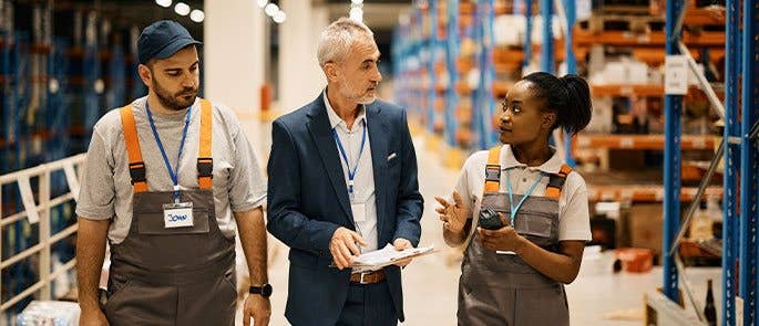 Employees speaking to the manager while walking through the warehouse