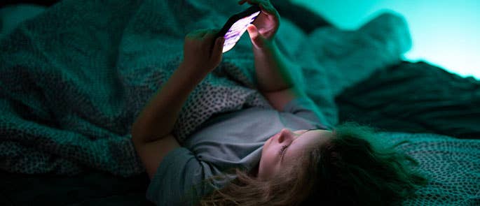 child doomscrolling on phone in bed instead of sleeping