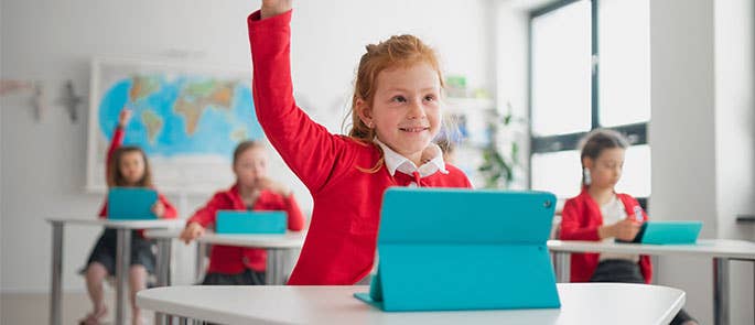child with hand raised in classroom