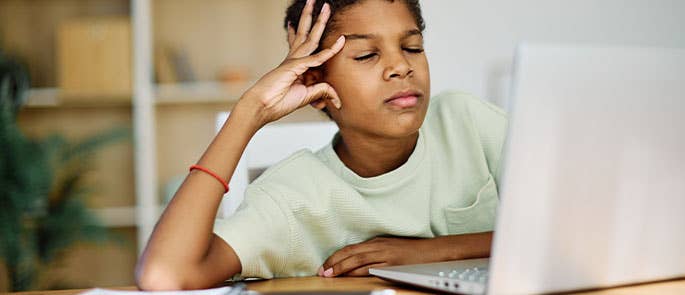 child in front of a laptop struggling to focus