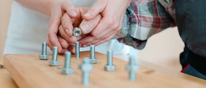 Occupational therapist helping patient with work task using nuts and bolts
