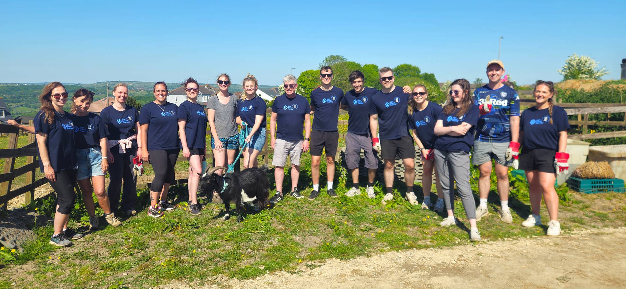 Members of the High Speed Training team stood with a goat after a day's volunteering at a horse sanctuary